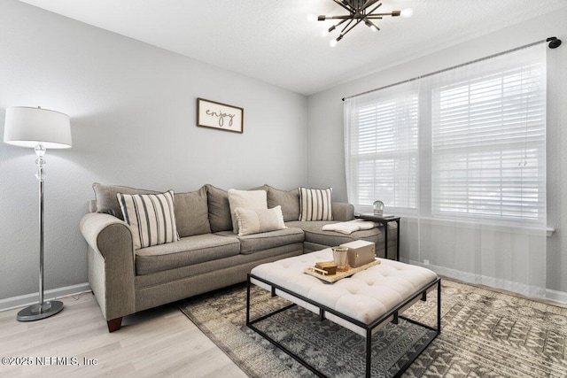 living area featuring baseboards, light wood finished floors, and a textured ceiling