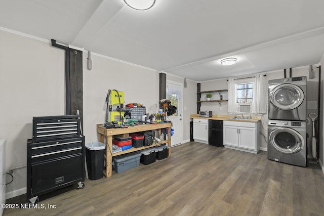 clothes washing area with dark wood-style floors, stacked washing maching and dryer, baseboards, and a sink