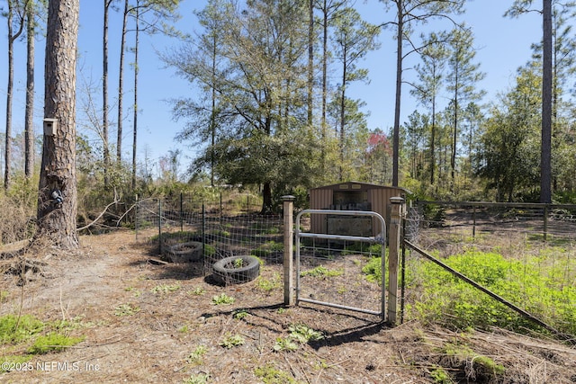 view of gate with an outbuilding, a pole building, and fence