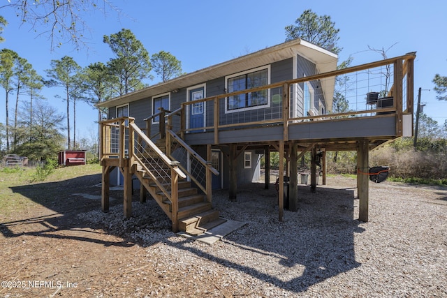 rear view of house featuring stairs, a carport, and a wooden deck