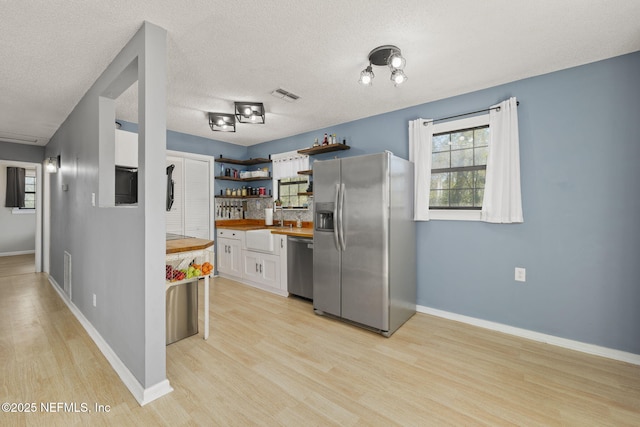 kitchen featuring visible vents, light wood-style flooring, open shelves, appliances with stainless steel finishes, and wooden counters