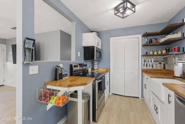 kitchen featuring open shelves, light wood-style flooring, butcher block countertops, appliances with stainless steel finishes, and white cabinetry