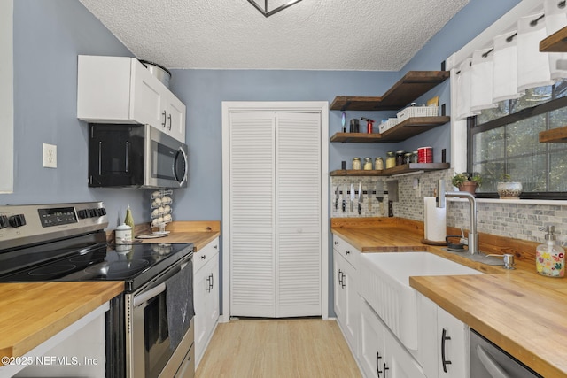 kitchen featuring butcher block countertops, stainless steel appliances, and open shelves