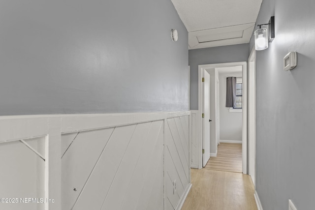 hallway featuring attic access and light wood finished floors