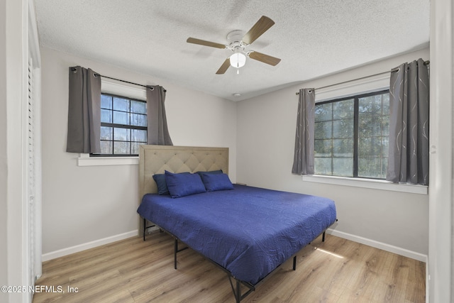 bedroom featuring a textured ceiling, baseboards, and wood finished floors