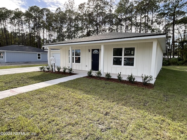 view of front of home with a front lawn, covered porch, board and batten siding, concrete driveway, and roof with shingles