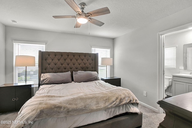 bedroom featuring ensuite bath, carpet flooring, baseboards, and a textured ceiling