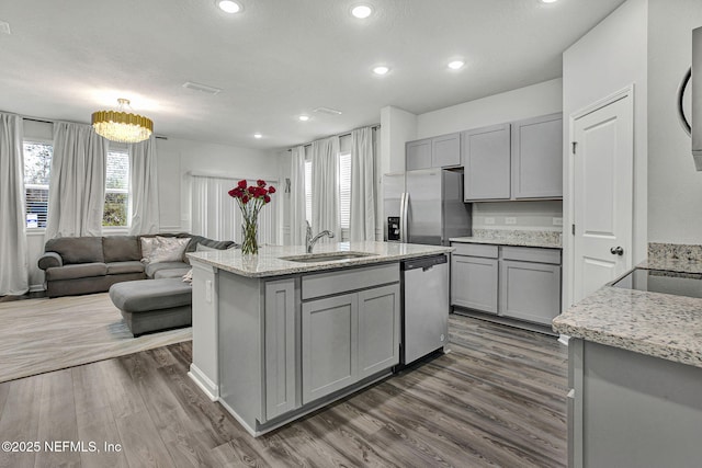 kitchen with a sink, dark wood-type flooring, appliances with stainless steel finishes, and gray cabinets