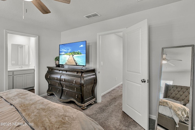 carpeted bedroom with visible vents, connected bathroom, baseboards, a ceiling fan, and a sink