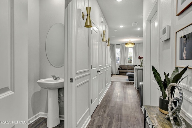 hall with dark wood-type flooring, recessed lighting, visible vents, and a sink