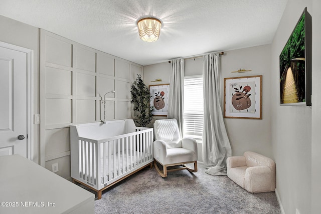 carpeted bedroom featuring a crib and a textured ceiling