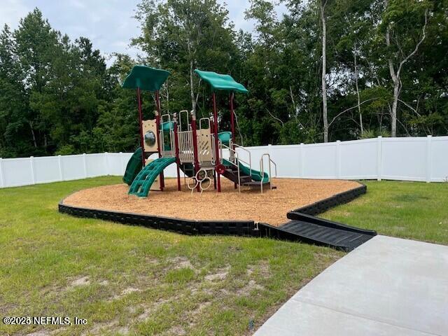 communal playground featuring a lawn and a fenced backyard