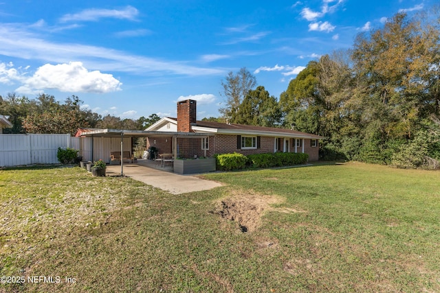 back of house with a patio, fence, a yard, brick siding, and a chimney