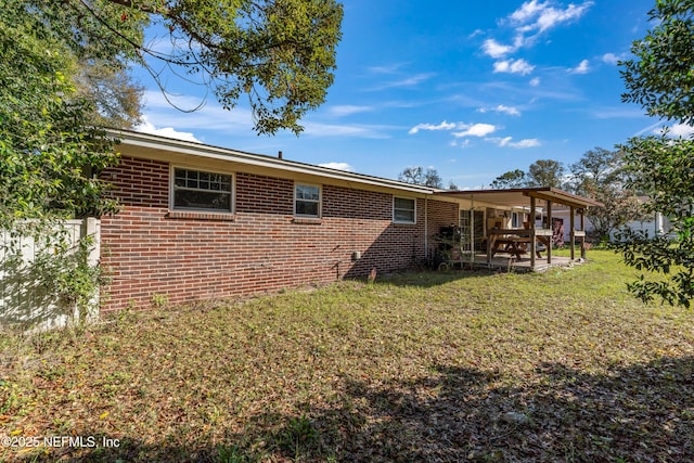 back of house with a patio, a lawn, and brick siding