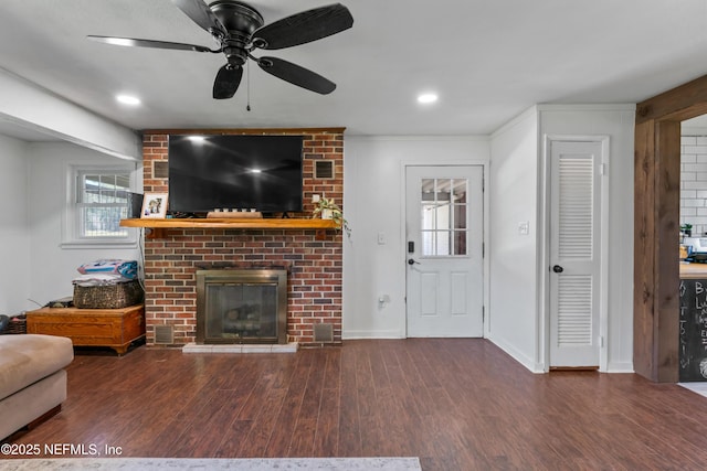 living room with a ceiling fan, a brick fireplace, wood finished floors, and baseboards