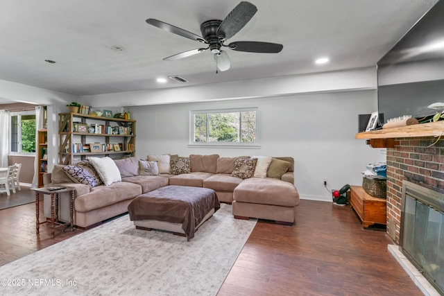 living area with dark wood finished floors, a brick fireplace, baseboards, and visible vents