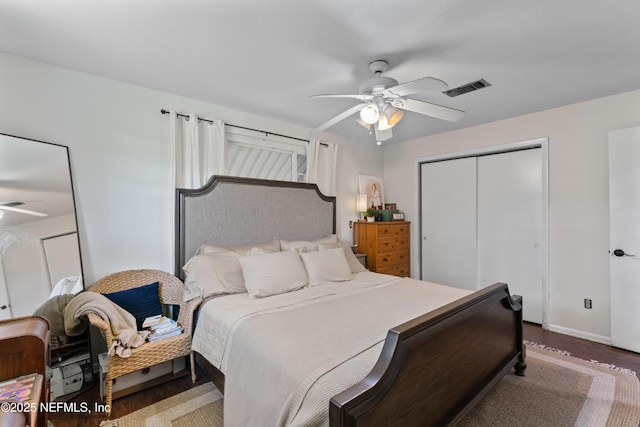 bedroom with a ceiling fan, wood finished floors, visible vents, baseboards, and a closet