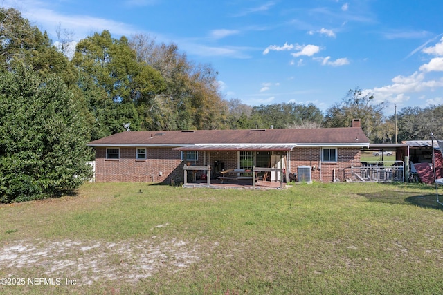 rear view of house featuring brick siding, central AC unit, a patio area, and a lawn