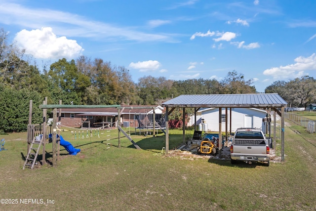 view of yard featuring fence, a carport, and a playground