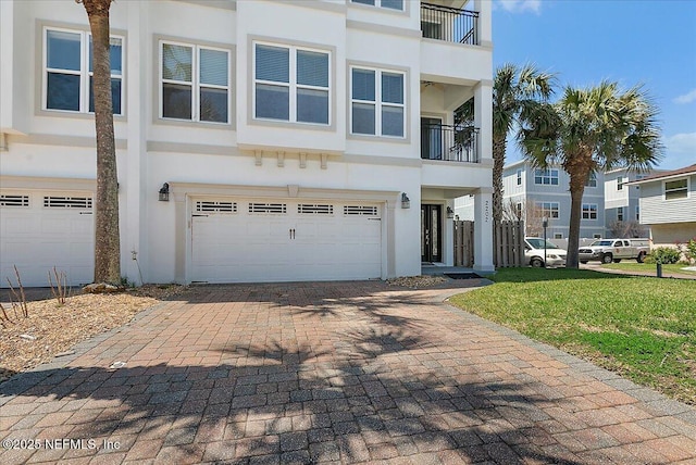 view of front of house with a front yard, an attached garage, driveway, and stucco siding