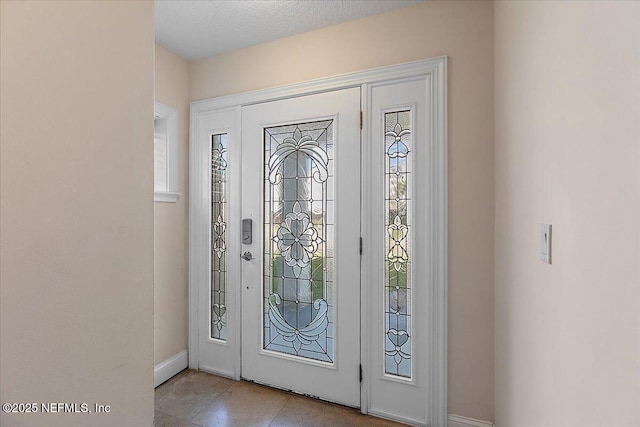 foyer with baseboards and a textured ceiling