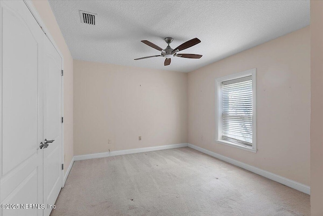 carpeted empty room featuring visible vents, baseboards, a textured ceiling, and ceiling fan