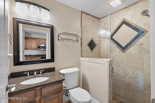 full bathroom with vanity, toilet, a shower stall, and a textured ceiling