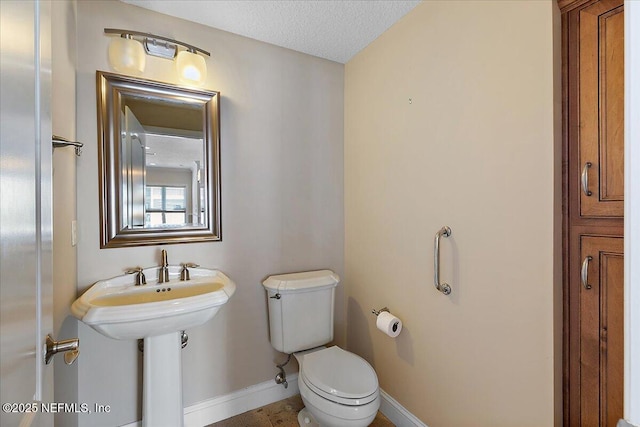 half bath featuring toilet, baseboards, and a textured ceiling