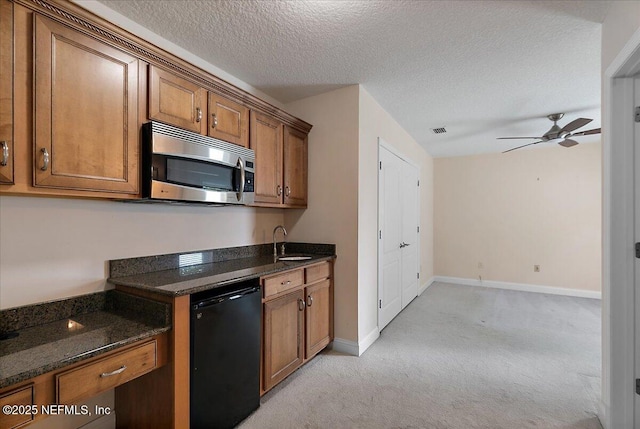 kitchen with brown cabinetry, a sink, dishwasher, stainless steel microwave, and light colored carpet