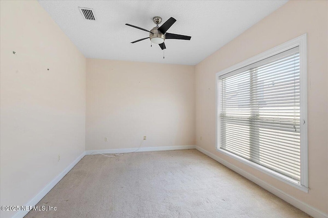 carpeted spare room featuring visible vents, baseboards, and a ceiling fan