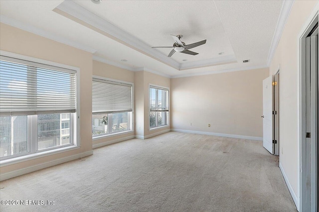 unfurnished room featuring a raised ceiling, ornamental molding, a ceiling fan, baseboards, and light colored carpet