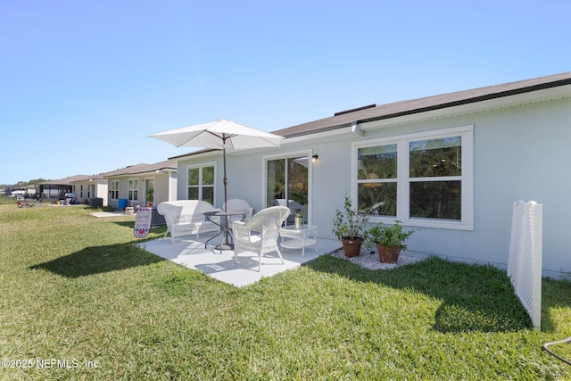 rear view of property featuring a yard, a patio area, and stucco siding