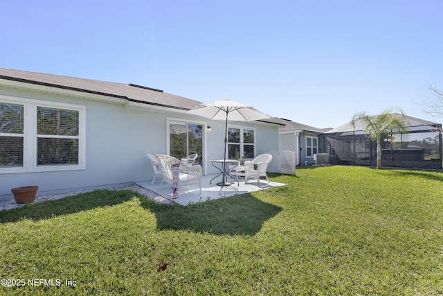 rear view of house with a lawn, cooling unit, a patio, and stucco siding