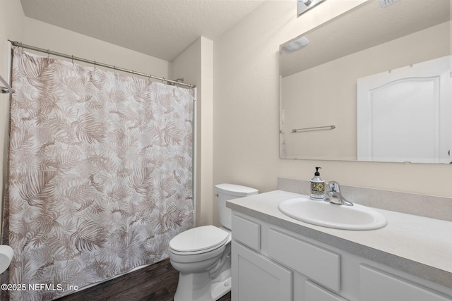 full bathroom featuring vanity, wood finished floors, a textured ceiling, curtained shower, and toilet