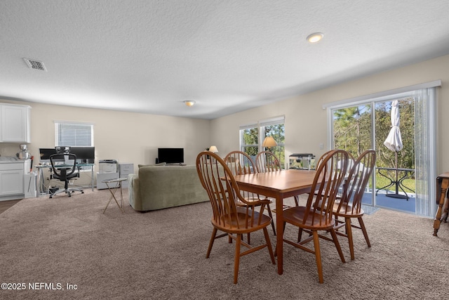 dining room with plenty of natural light, a textured ceiling, visible vents, and carpet floors