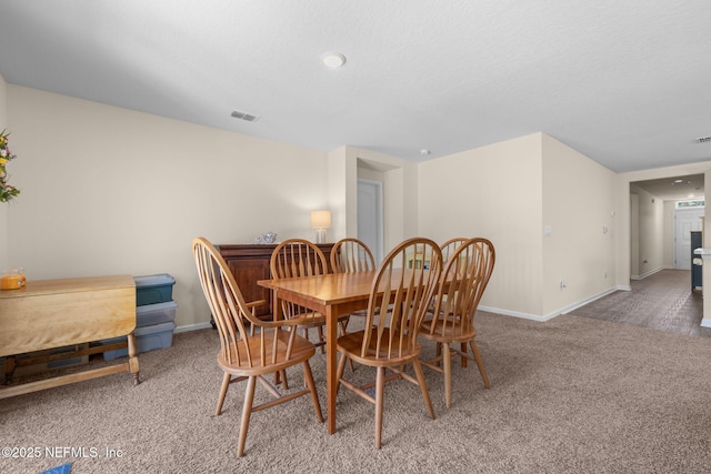 carpeted dining room with baseboards and visible vents