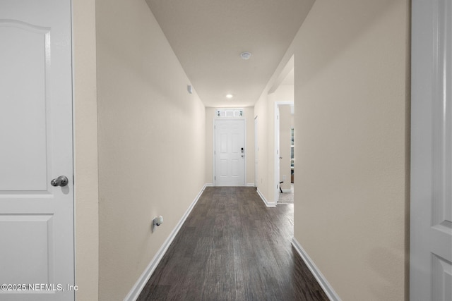 hall featuring dark wood-type flooring, visible vents, and baseboards