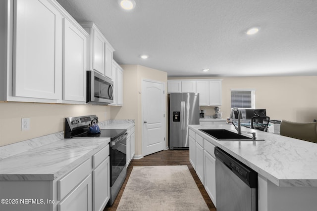 kitchen with a sink, appliances with stainless steel finishes, a kitchen island with sink, and white cabinetry