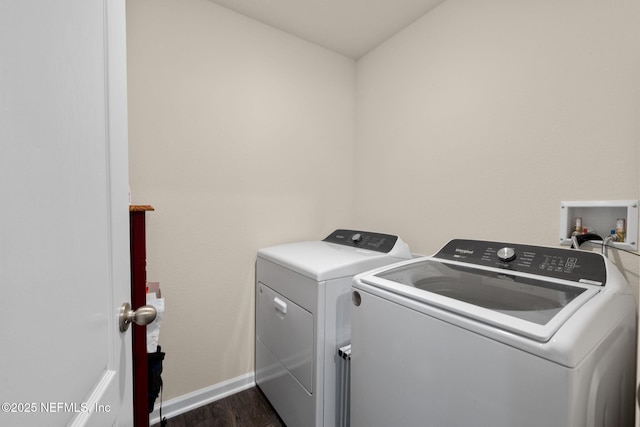 laundry area featuring dark wood finished floors, laundry area, separate washer and dryer, and baseboards