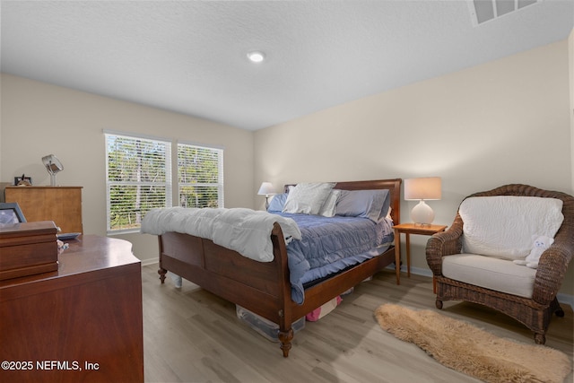 bedroom with visible vents, baseboards, and wood finished floors