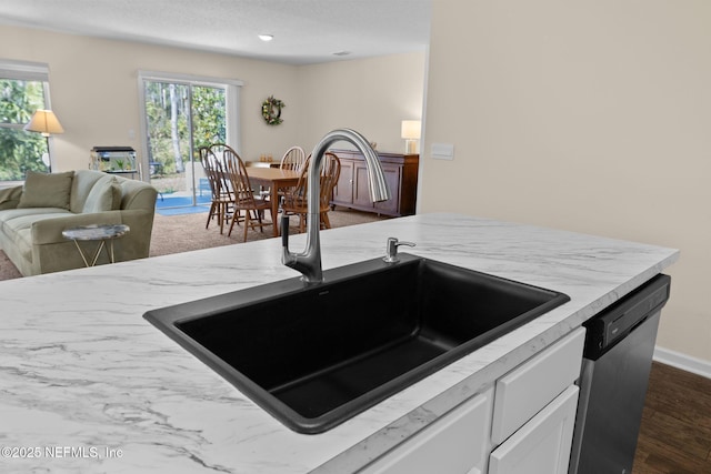 kitchen featuring white cabinetry, dark wood-style flooring, a sink, dishwasher, and open floor plan