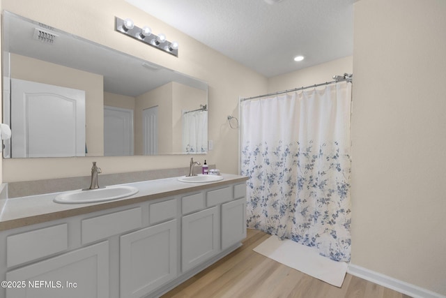 bathroom featuring double vanity, visible vents, wood finished floors, and a sink