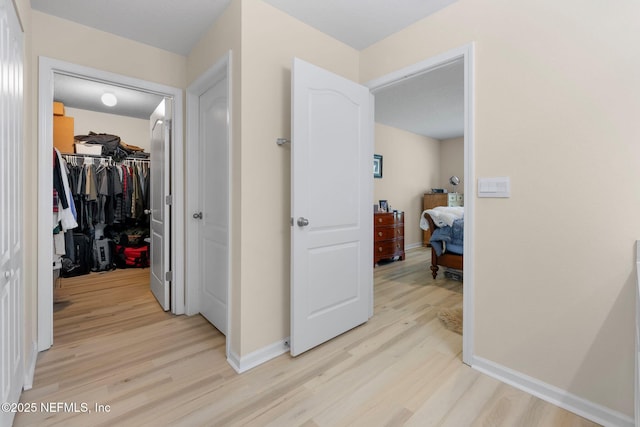 corridor with baseboards and light wood finished floors