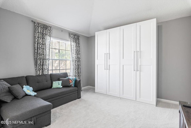 living area with baseboards, light colored carpet, and vaulted ceiling