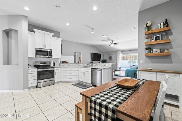 kitchen featuring ceiling fan, light tile patterned floors, appliances with stainless steel finishes, a peninsula, and a sink