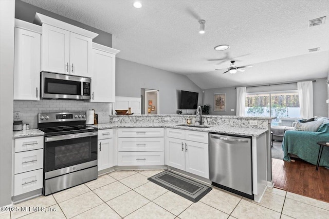 kitchen with visible vents, a peninsula, a sink, appliances with stainless steel finishes, and open floor plan