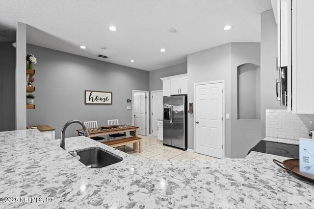 kitchen featuring visible vents, light stone counters, appliances with stainless steel finishes, white cabinetry, and a sink