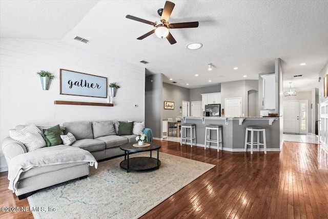 living area with visible vents, a textured ceiling, ceiling fan, and dark wood-style flooring