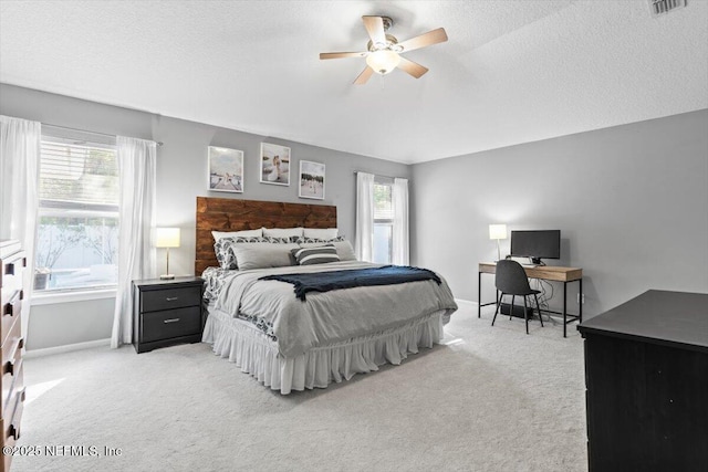 bedroom featuring light carpet, a textured ceiling, and ceiling fan