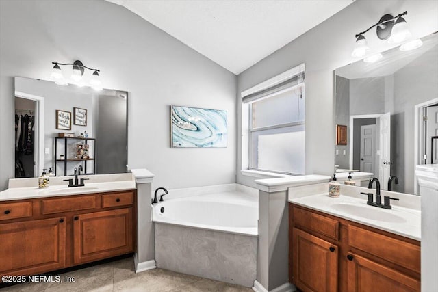 bathroom with a sink, two vanities, a garden tub, and vaulted ceiling